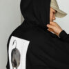 A person wearing a hat and a black hoodie.