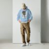 A man standing in front of a white wall wearing a blue hoodie.