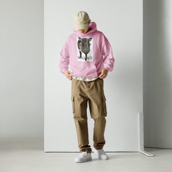 A person standing in front of a white wall wearing a pink hoodie.